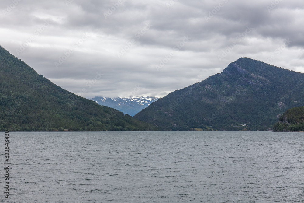 Norwegian fjord and mountains surrounded by clouds, ideal fjord reflection in clear water. selective focus. Norwegian fjord and mountains surrounded by clouds, ideal fjord reflection in clear water. selective focus.