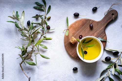 Overhead view of Fresh black olives and extra virgin olive oil with olive branches arranged on a wooden chopping boards
