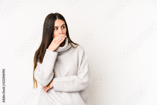 Young caucasian woman isolated on a white background thoughtful looking to a copy space covering mouth with hand.