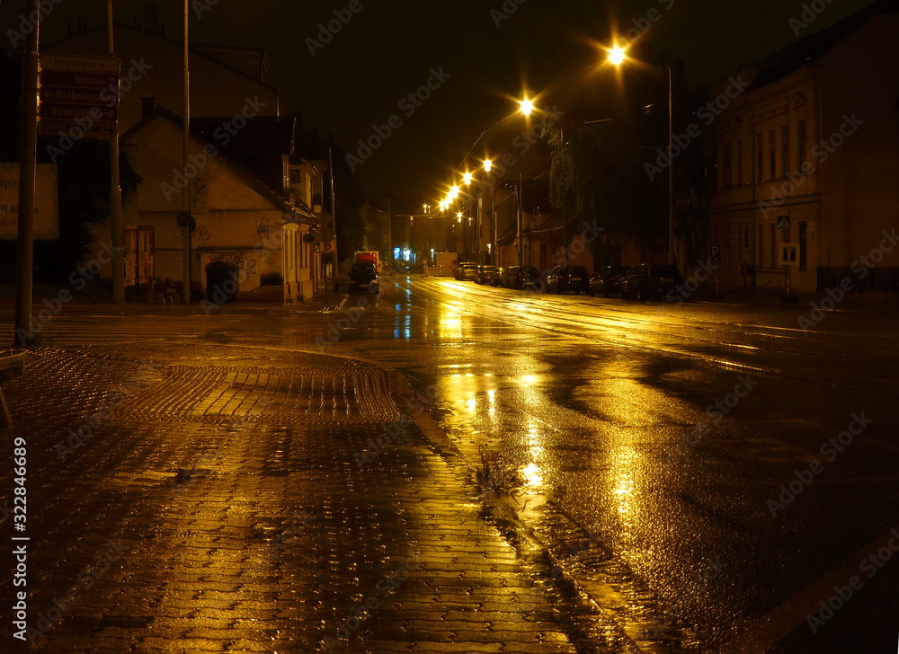 Photo of a a wet empty street at night illuminated by street lamps