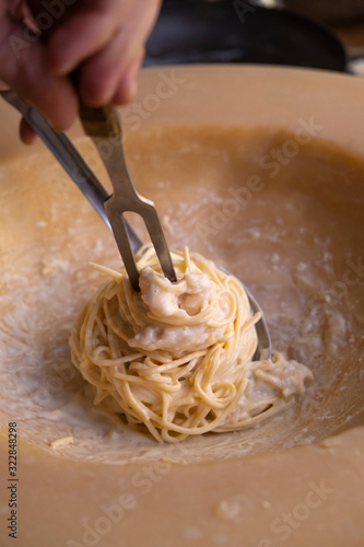 Close-up of a Man preparing spaghetti in a padano grana cheese wheel (pasta alla ruota) photo