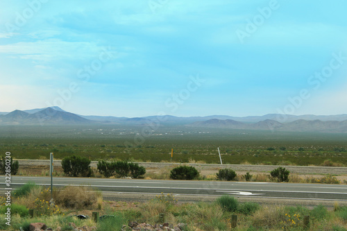 A wide open landscape with a clear blue sky and an empty road