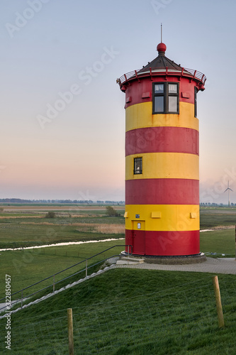 Red and yellow striped Pilsum lighthouse in Germany.