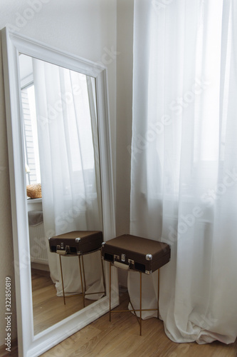 white mirror and white drapes brown suitcase in cozy bright interior living room
