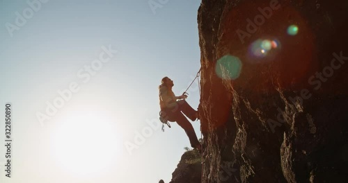 Professional caucasian alpinist is climbing up a cliff during hot day, using special equipment - extreme tourism concept 4k footage