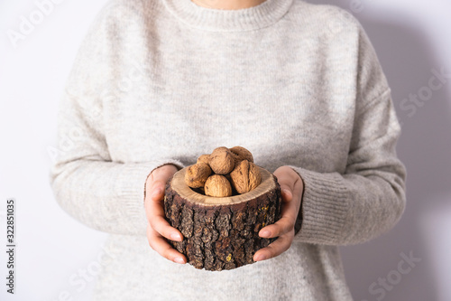 Shelled walnuts women's hand in wooden bowl. Natural, healthy and tasty snakcs. photo