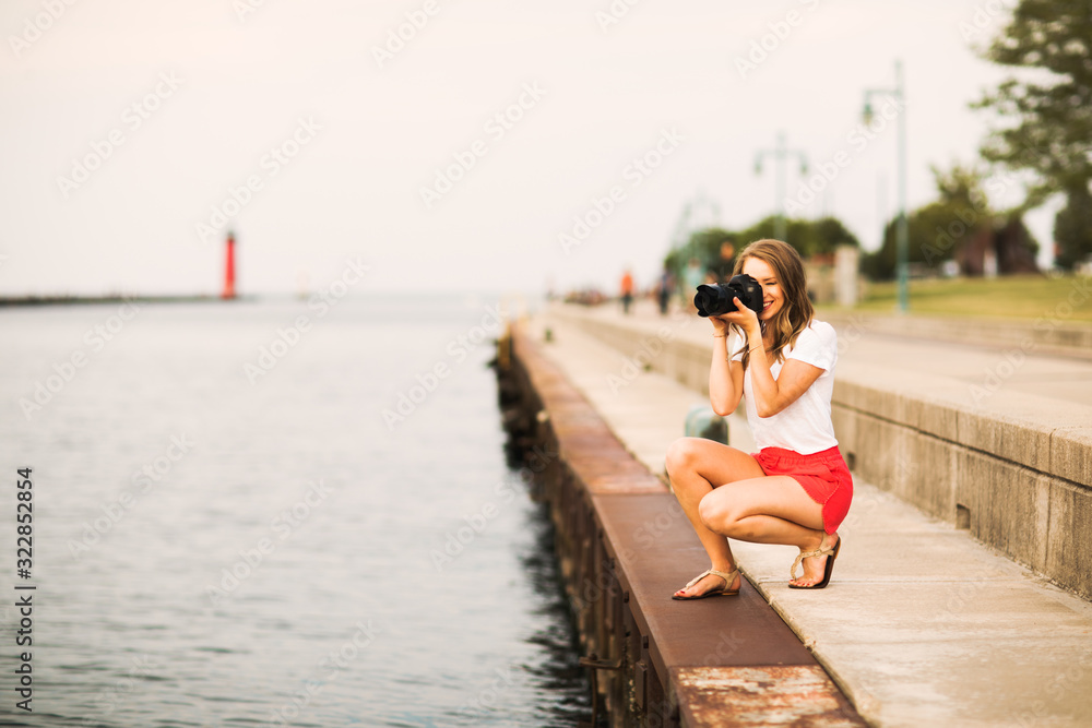 young woman photographer - taking photos of sunset off lake 