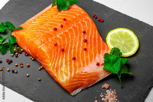 Fresh raw salmon with parsley .lemon pepper and salt on slate plate, closeup.