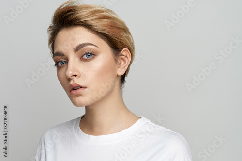 Portrait of young female model with short hair isolated on gray background