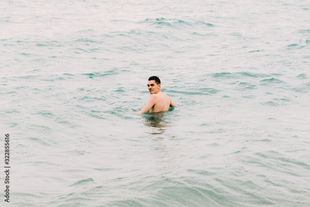 a young guy is swimming in the blue clear water of the ocean