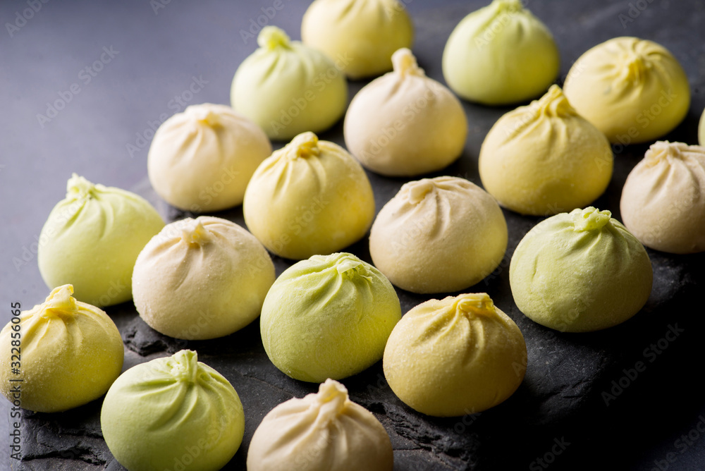 Fototapeta premium frozen khinkali and dumplings on a dark background with ingredients and spices. Semi-finished products