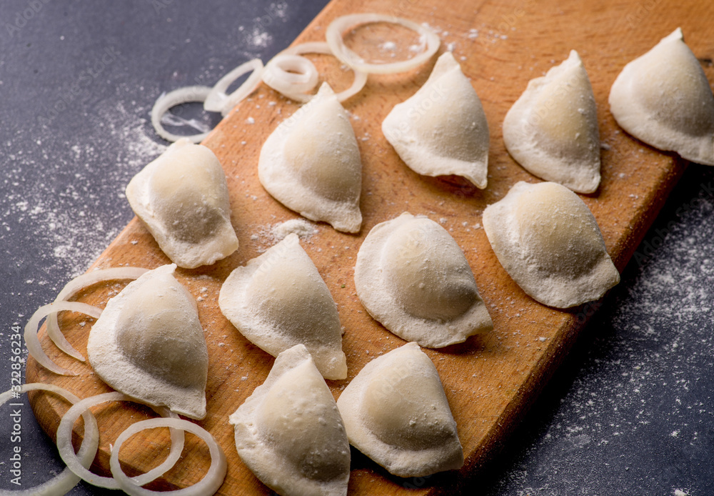 frozen khinkali and dumplings on a dark background with ingredients and spices. Semi-finished products frozen khinkali and dumplings on a dark background with ingredients and spices. Semi-finished products