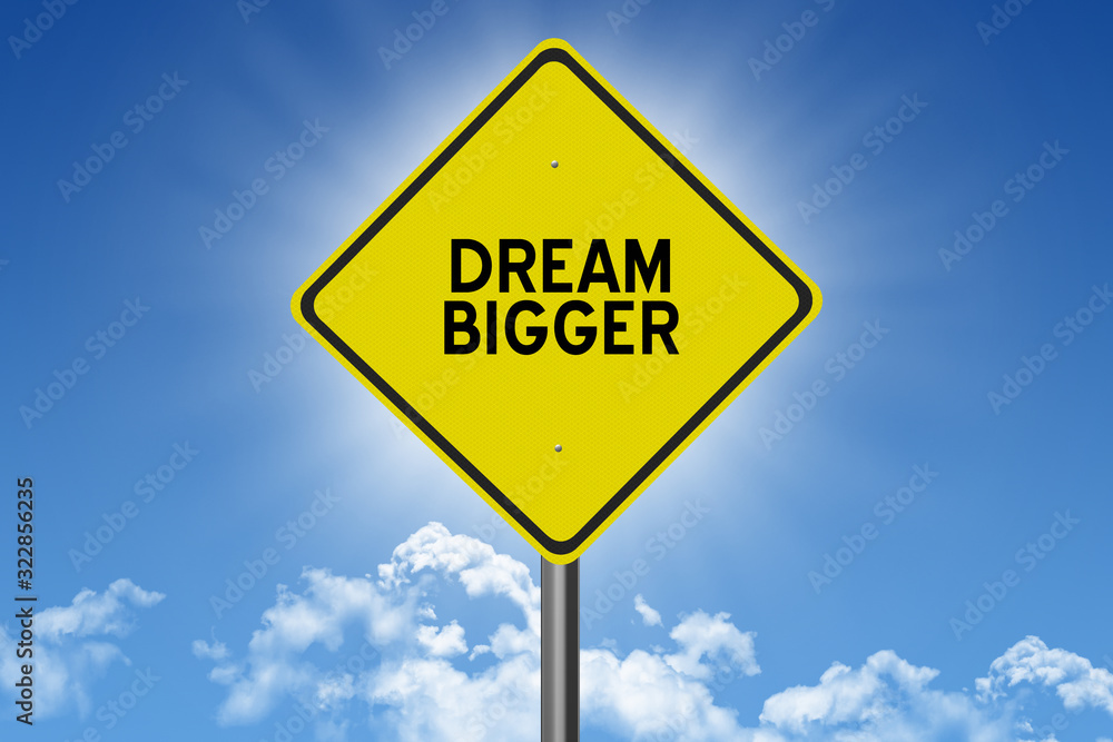 Dream Bigger inspirational quote on sky background for success in planning and goals concept. Dream Bigger inspirational quote on sky background for success in planning and goals concept.