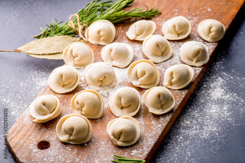 frozen khinkali and dumplings on a dark background with ingredients and spices. Semi-finished products