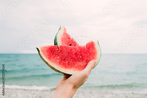 a slice of ripe juicy watermelon in the hands of the sea