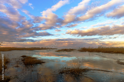 There is a panorama of lake Peipus at sunset in the spring. The shores of the lake are overgrown with reeds. Pskov region, Russia. © 1802185