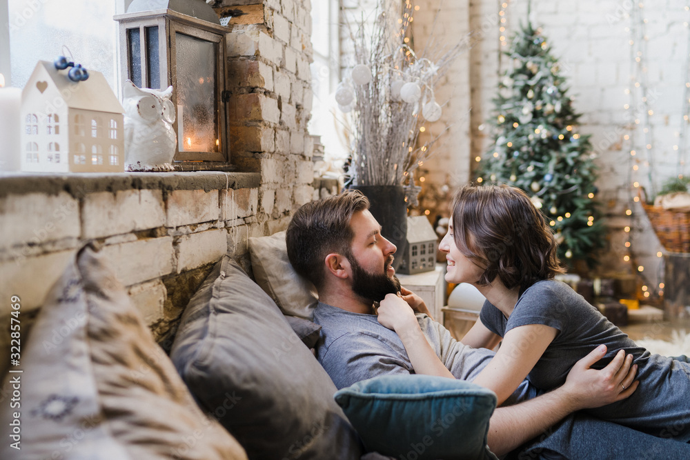 Winter weekend at home. Young caucasian couple in cozy clothes hugging in bed. Celebrating Christmas, Valentine, love, romance concept.