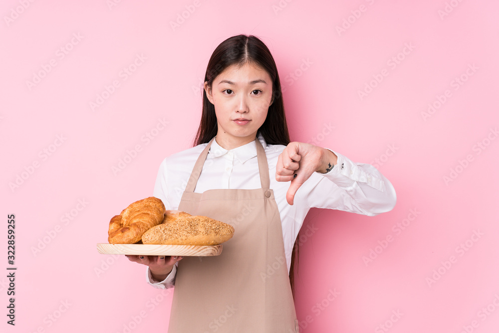 Young chinese baker woman isolated showing a dislike gesture, thumbs down. Disagreement concept. Young chinese baker woman isolated showing a dislike gesture, thumbs down. Disagreement concept.