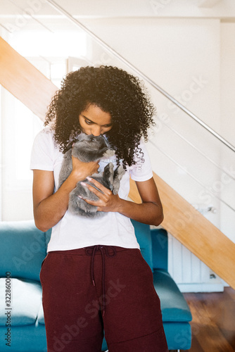 Young black lady coddling rabbit at home photo