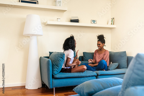 Pleased black females playing had clap game on sofa