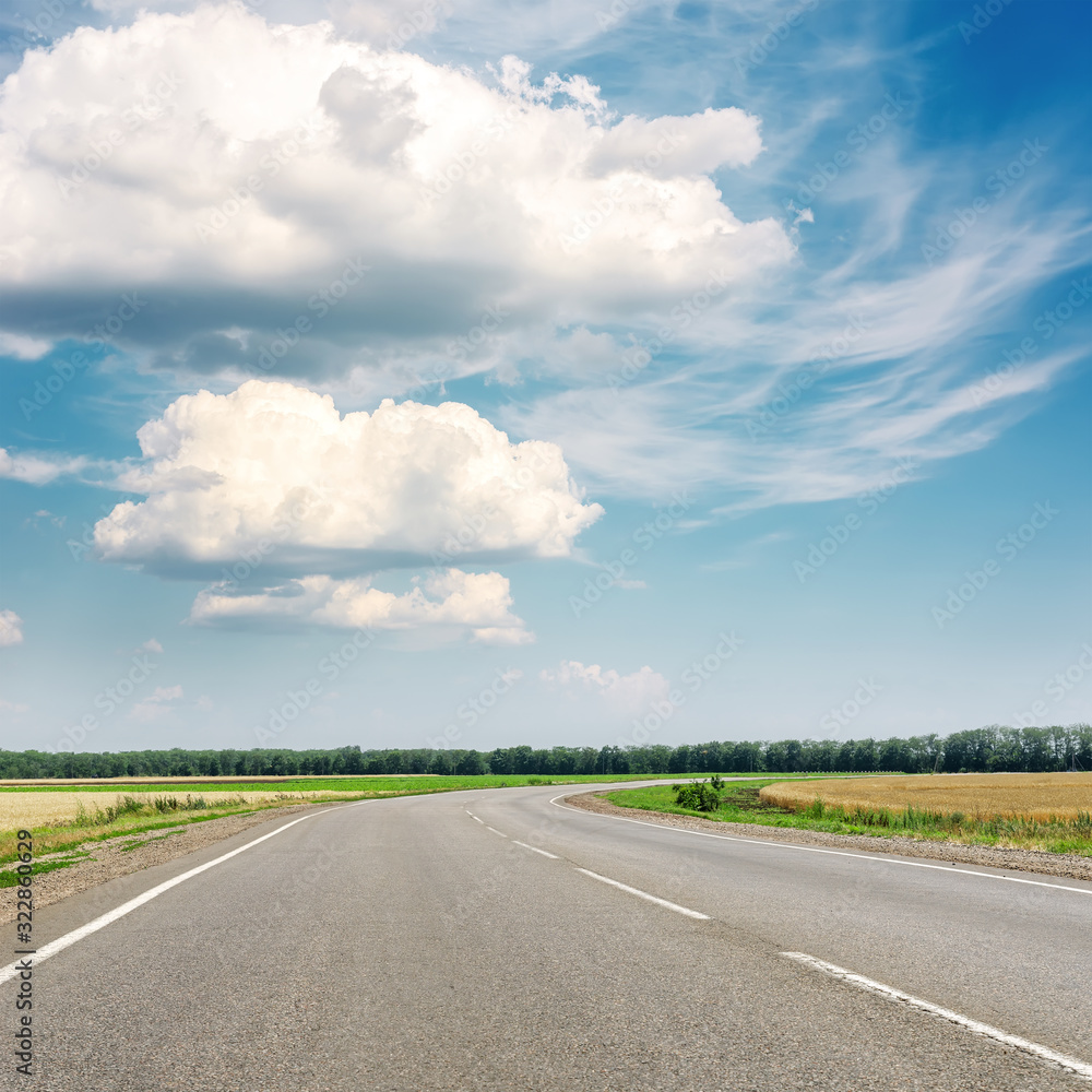 asphalt road to horizon and blue sky with clouds over it asphalt road to horizon and blue sky with clouds over it