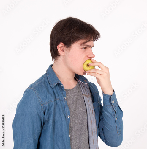 Studio shot image of young sporty man who is eating apple.