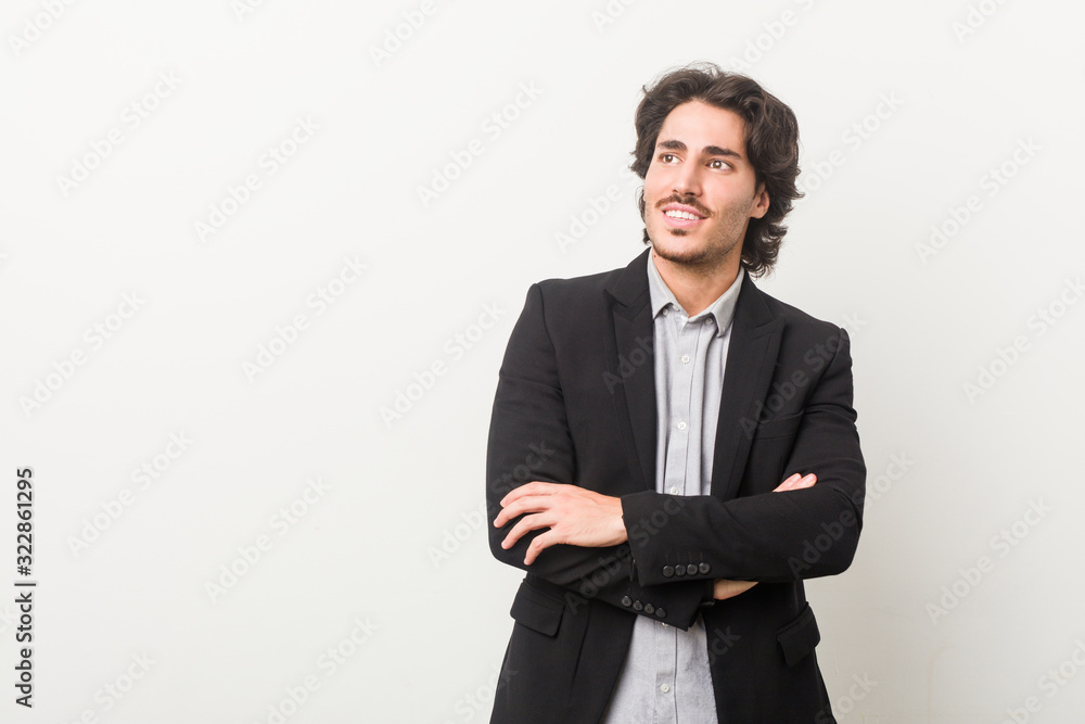 Young business man against a white background smiling confident with crossed arms.