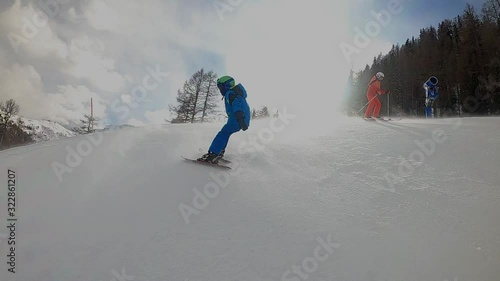 Little boy skiing in the Alpine resort. A 6 year old child enjoys a winter holiday with his mother. Stabilized footage. Slow motion. Strong wind, gale