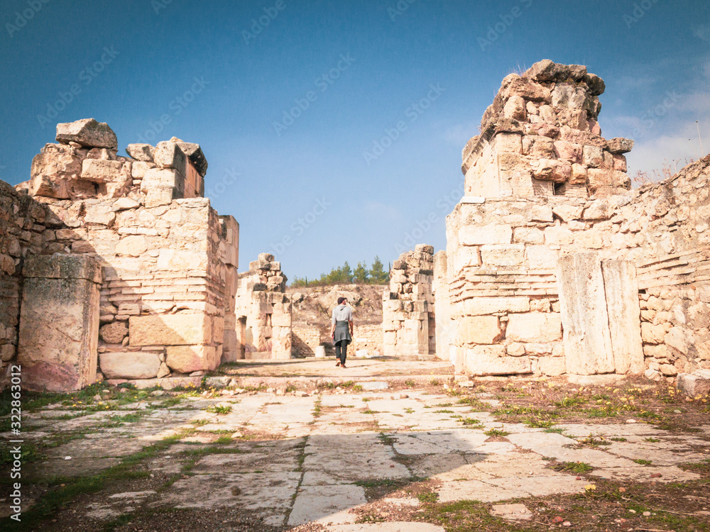Tourist is standing and looking around surounded by archeological sites. Concept of solo exploration of historical places. Hierapolis.Turkey.