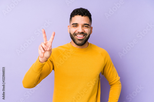 Young mixed race arabic man isolated showing victory sign and smiling broadly.