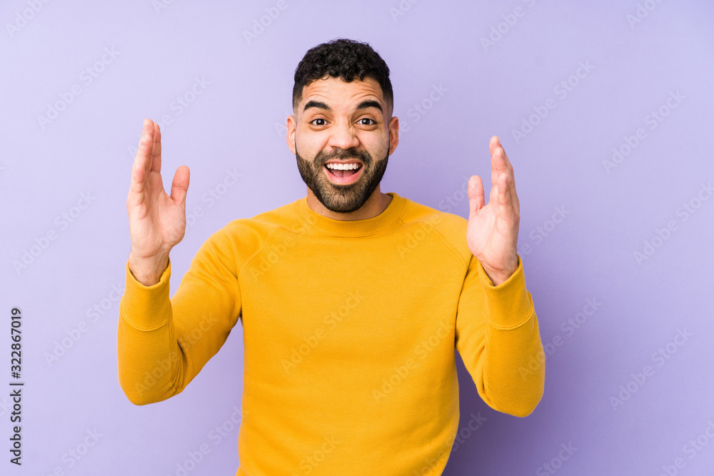 Young mixed race arabic man isolated receiving a pleasant surprise, excited and raising hands. Young mixed race arabic man isolated receiving a pleasant surprise, excited and raising hands.