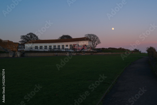 The almost full super 'snow' moon rising over the boating lake building on the promenade of Ramsgate west cliff