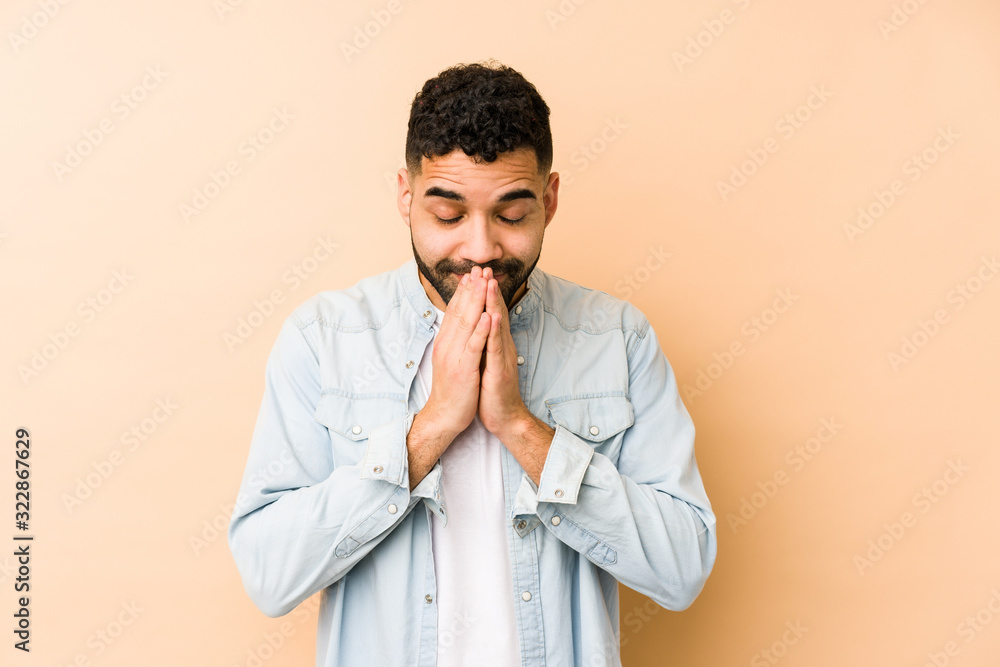 Young mixed race arabic man isolated holding hands in pray near mouth, feels confident. Young mixed race arabic man isolated holding hands in pray near mouth, feels confident.