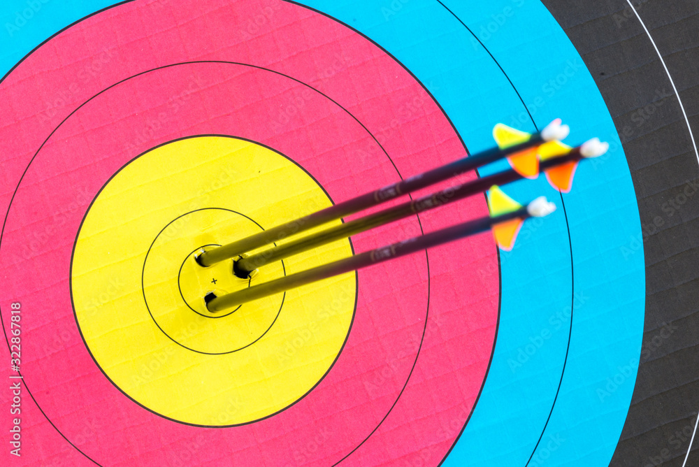 Shooting for gold. Three black arrows in the bulls eye of an archery target Shooting for gold. Three black arrows in the bulls eye of an archery target