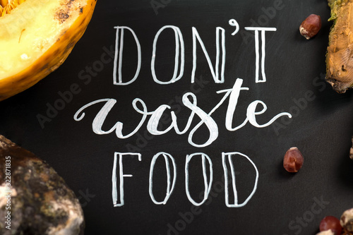 Close up of a chalkboard with Don't waste food lettering and rotten fruits. Selective focus