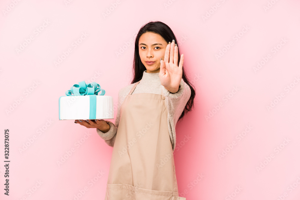 Young chinese woman holding a cake isolated confused, feels doubtful and unsure.