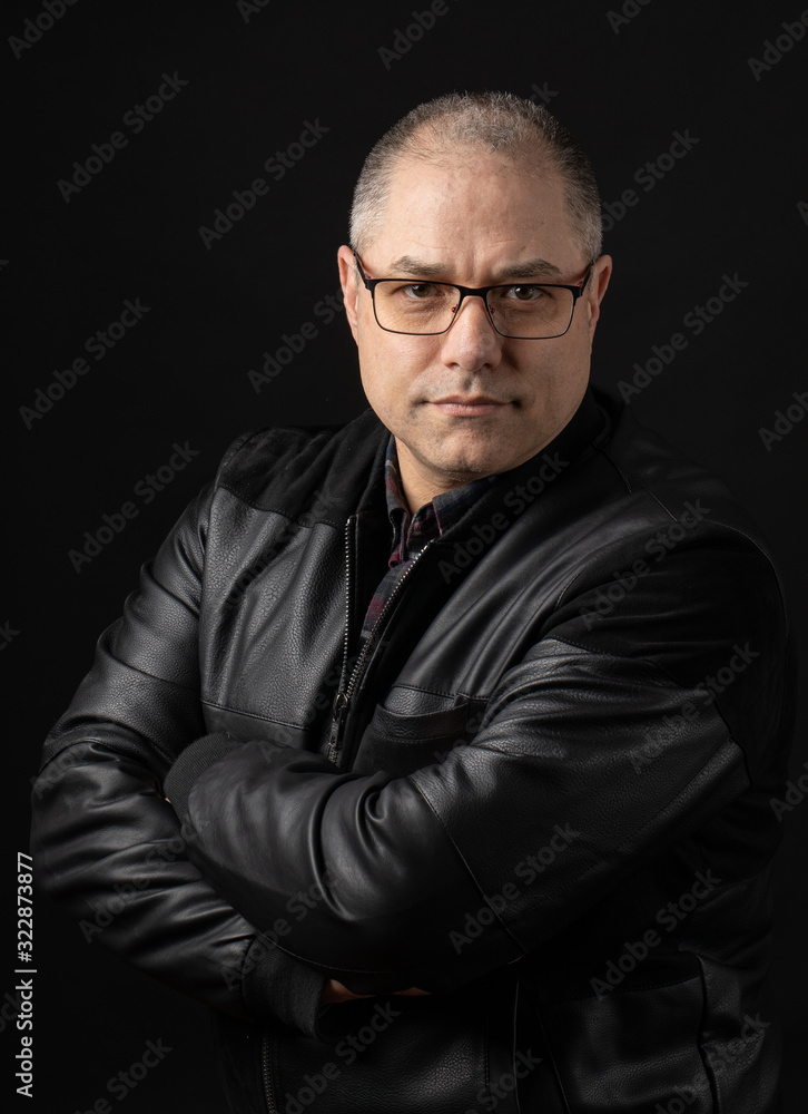 Portrait of man wearing leather jacket on dark background in studio