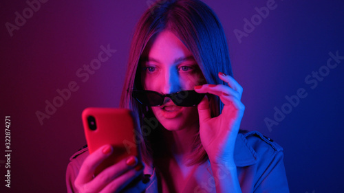 Footage of beautiful surprised Caucasian young woman with open mouth wearing black sunglasses reading message in neon lights. Big blue eyes. Good news. Bob hairstyle.