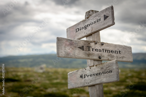 Diagnosis, treatment and prevention text on wooden road sign outdoors in nature. Illness, medical, Corona virus, ncov and covid-19 concept.