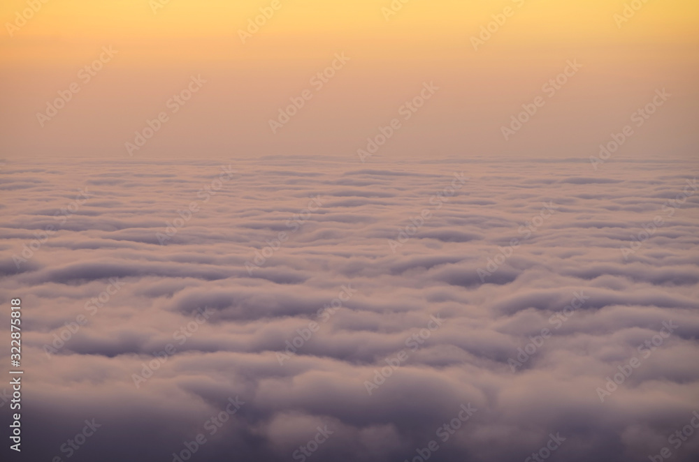 Above the clouds, the view from the cockpit . A photo above the clouds during sunrise or sunset. pink sky.