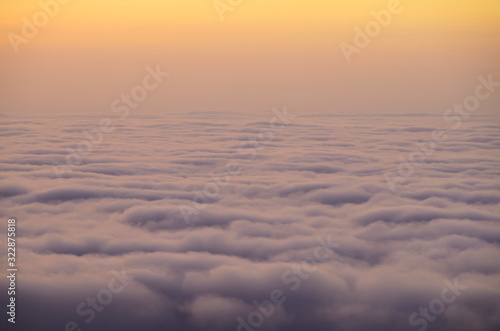 Above the clouds, the view from the cockpit . A photo above the clouds during sunrise or sunset. pink sky. © kato72