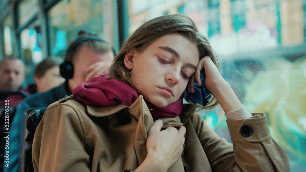 Fototapeta premium Portrait young attractive woman look on window on the tram on a cold autumn day at the start of the flu season disease fever flu grippe health illness infection influenza migraine sickness slow motion