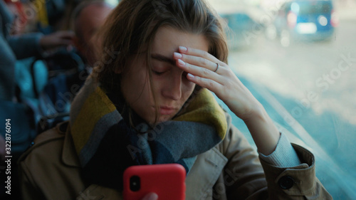 Young woman use phone headache feel bad on the tram cold autumn day flu season disease fever grippe health illness infection influenza migraine sickness slow motion