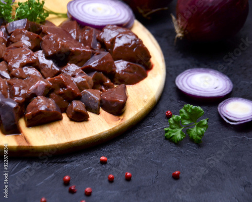 Wallpaper Mural fresh chunks of beef liver on a cutting Board next to onions and spices on a wooden black table selective Torontodigital.ca