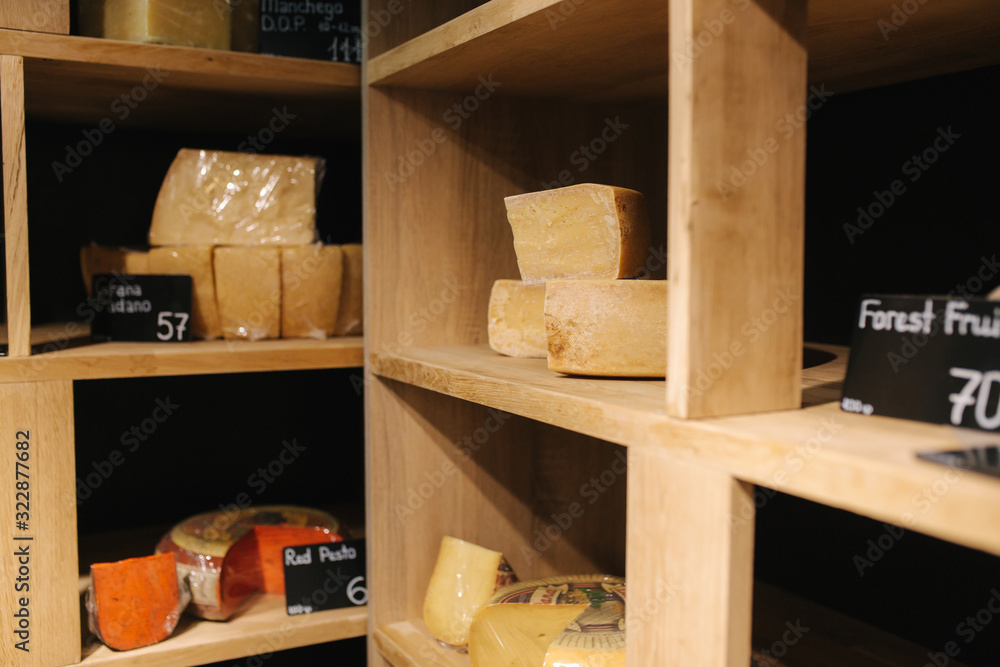 Shelf with cheese in cheese store. Assortment of different cheese types