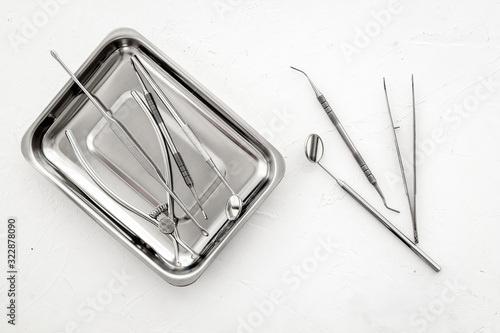 Stomatological tools in tray on dentist's desk on white background top-down