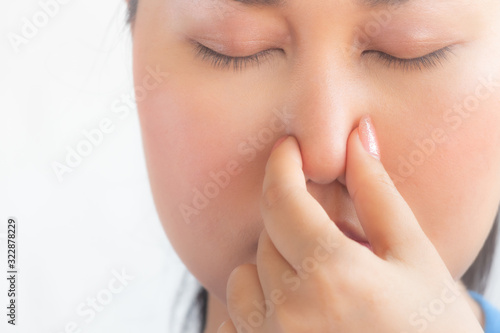 young pretty woman feeling disgusted, holding nose to avoid smelling a foul and unpleasant stench against white background,asian woman feel smell foul in white background.