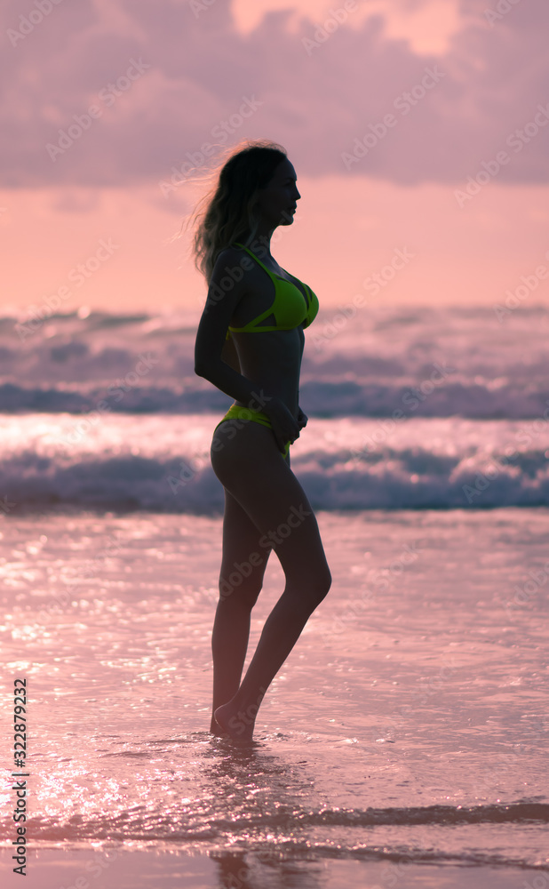 Slender female Silhouette on a background of sea waves and the sky with the setting sun