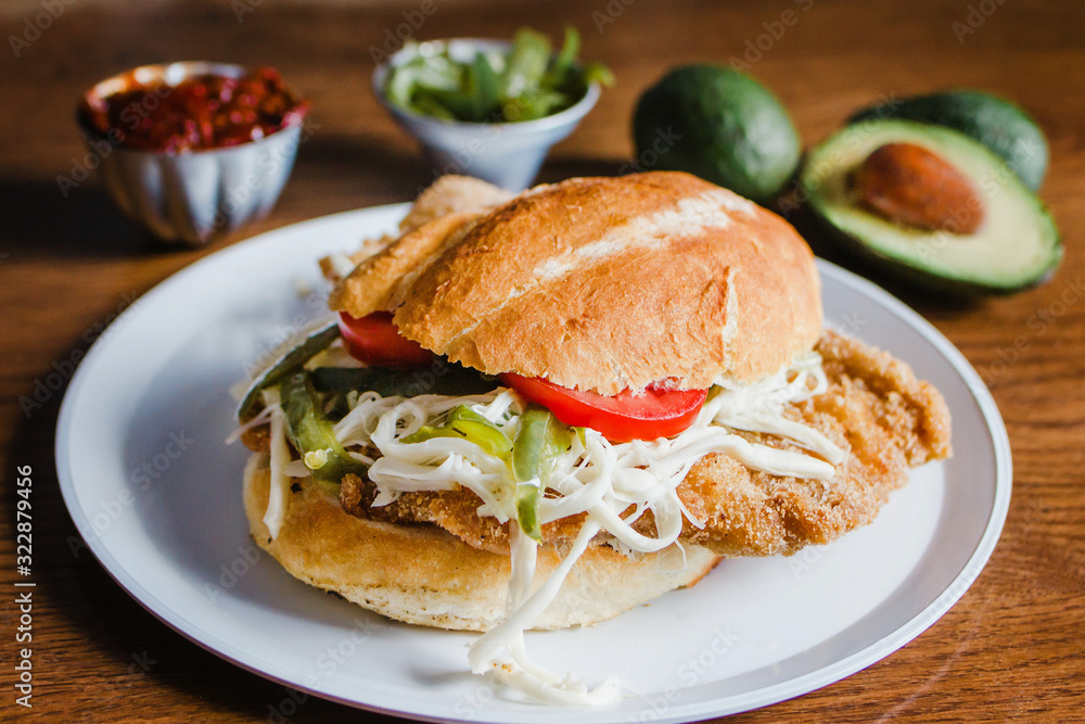 Mexican torta is chicken milanese sandwich with avocado, chili chipotle and oaxaca cheese