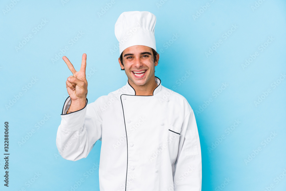 Young cook man isolated joyful and carefree showing a peace symbol with fingers. Young cook man isolated joyful and carefree showing a peace symbol with fingers.